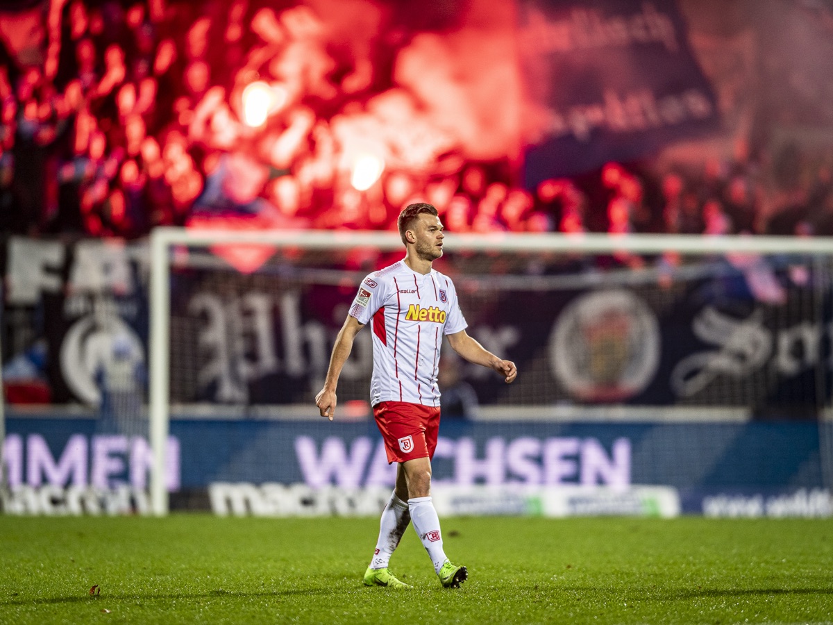 Spieler vor rotem Pyro-Rauch der Fankurve, Karlsruher SC gegen SSV Jahn Regensburg
